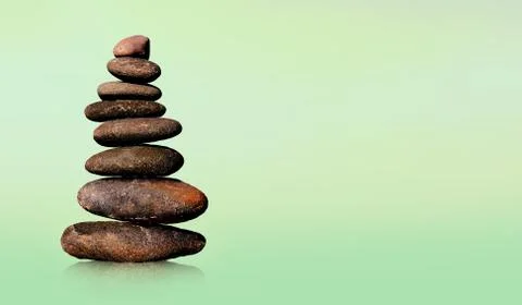 Stone-stacking or rock balancing with green background. Stock Photos