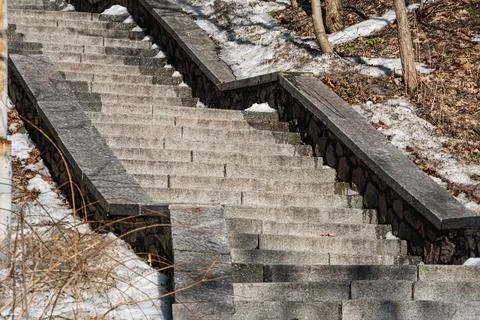 Stone staircase leading upwards, bordered by low stone wall, set against natu Stock Photos