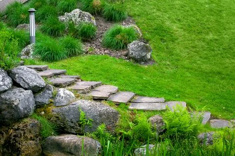 Stone staircase with steps made of wild natural stone on slope of hill park. Stock Photos