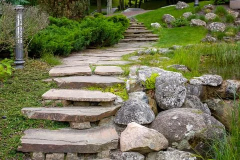 Stone staircase with steps made of wild natural stone on slope of hill park. Stock Photos