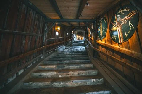 A stone staircase winds upwards inside a dimly lit wooden building. The walls Stock Photos