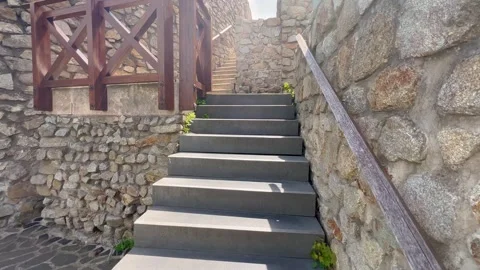 Stone stairs lead upward between ancient stone walls, illuminated by sunlight Stock Footage 297762071