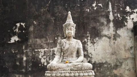 Stone statue of Buddha and old temple wall in the background. Slow motion 4k Видео 303684340