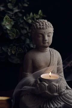 Stone statue of buddha with a candle Stock Photos