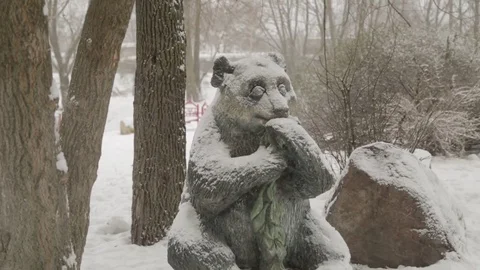 Stone statue of sitting panda during a snowfall on a winter day 動画素材 70345253