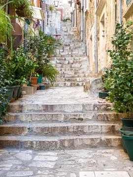 Stone steps on empty steep alley-street with cobblestone stairs Stock Photos