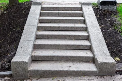 Stone steps of gray granite blocks on a slope in a park. Stock Photos