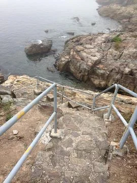 Stone steps leading down to rocky coastline Stock Photos