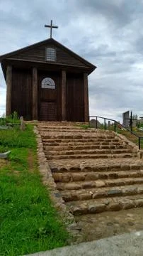 Stone steps leading to a old small wooden church surrounded by a cemetery Stock Photos