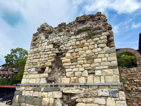 A stone structure stands with missing sections showing signs of age and weath Stock Photos