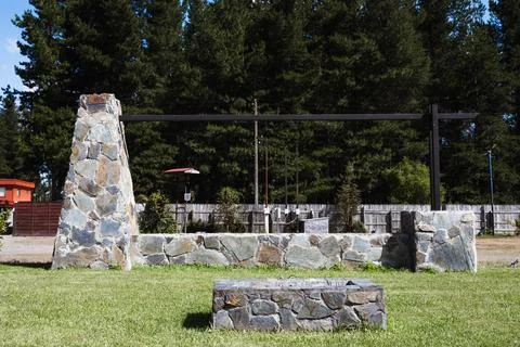 Stone structure stands tall, framed by lush green trees Фото