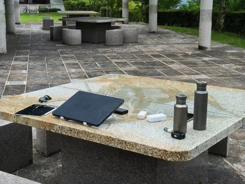 Stone table holds tech gadgets and water bottles Stock Photos