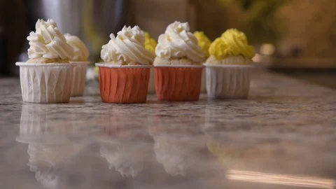 On stone tabletop there are several cupcakes, which from defocus turn into focus Stock Footage 127629478