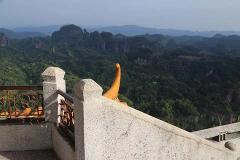 Stone terrace railing overlooking dense forest and rounded rock mountains Stock Photos