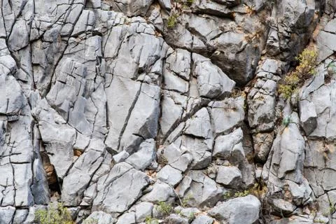 Stone texture close-up. Gray rock with cracks and with a rare green moss on i Stock Photos