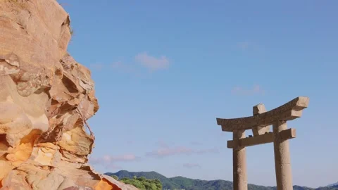Stone Torii gate under blue sky with golden sandstone rock formation on the side Stock Footage 340749743