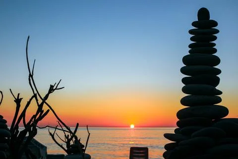 Stone tower and dry branches against sunset by the sea Stock Photos