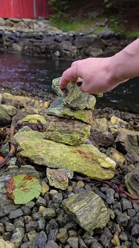 Stone tower assembling in reverse beside a flowing mountain stream Stock Footage 344058678