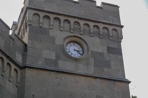 Stone Tower with Round Clock Face and Crenelations Stock Photos