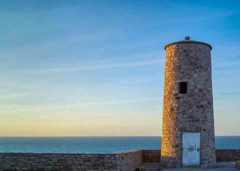 Stone tower by the sea at sunset Stock Photos