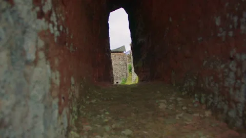 A stone tower seen through a narrow red rock tunnel Stock Footage 309357966