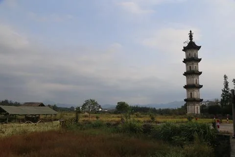 A stone tower stands in the middle of an open field, surrounded by rice fie.. Stock Photos