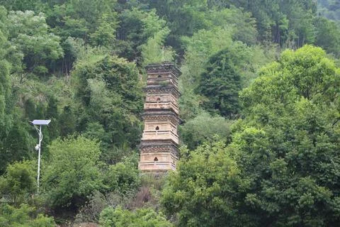 A stone tower stands on the mountain, surrounded by green trees and solar p.. Stock Photos