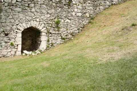 Stone town wall with small gate and courtyard with grass. Stock Photos