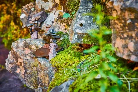 Stone wall at angle with cairn stone stack piles tiny in background and mossy Foto stock