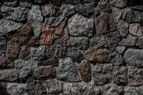 Stone wall as a background or texture. Wall with stones of various shapes and Photos