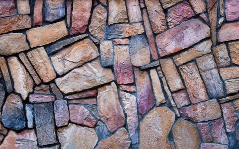 Stone wall background in vector. The wall is made of multi-colored natural stone Stock Illustration