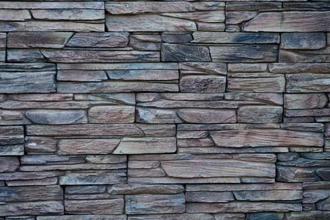 Stone wall with different shapes and colors arranged in a pattern. This desig Stock Photos