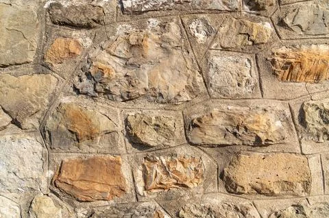 Stone wall displaying rough textured blocks in outdoor setting Stock Photos