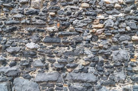 Stone wall displaying weathered masonry texture on exterior facade Stock Photos