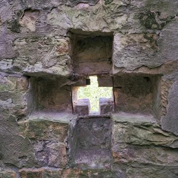Stone Wall Featuring an Intriguing CrossShaped Opening for Enhanced Visual Stock Photos
