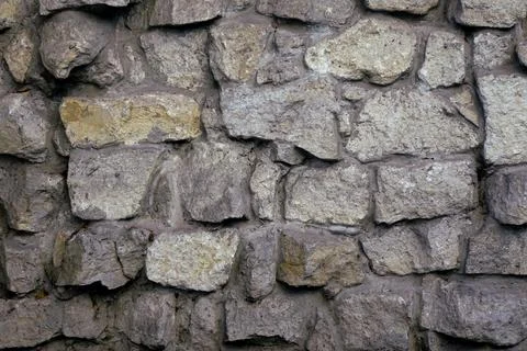 Stone wall of gray cobblestone and boulders with coarse cement bonds Stock Photos