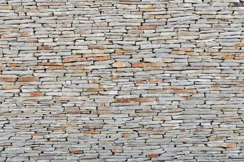 A stone wall made of small flat stones. Abstract and geometry concept. Stock Photos