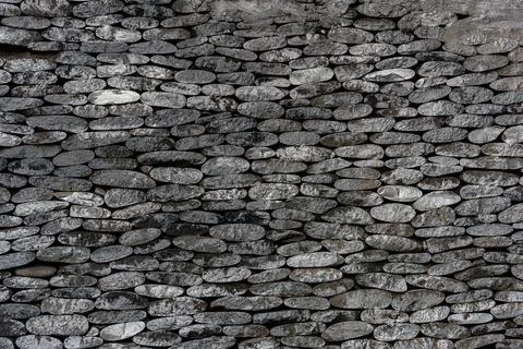 Stone wall made of stacked flat stones arranged horizontally. Stock Photos