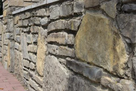 Stone wall made of various rocks in outdoor setting in daytime Stock Photos