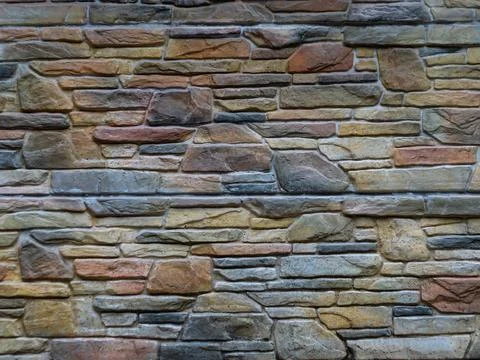 Stone wall of multi-colored natural stone with beautiful texture. Stock Photos