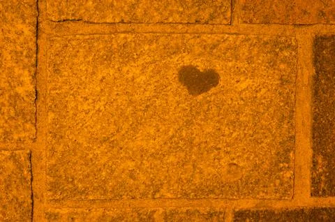 Stone wall with natural dark heart shaped pattern on rocks Stock Photos
