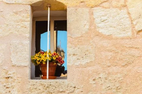 Stone wall with an old window and yellow flower pot Fotos de archivo