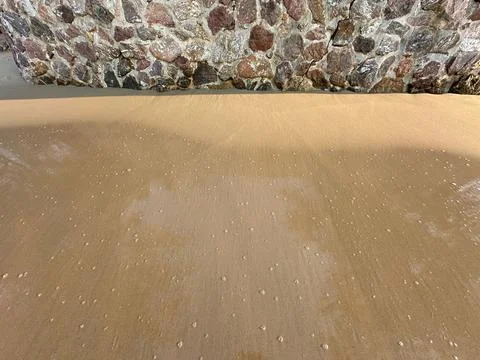 Stone wall sand beach Stock Photos