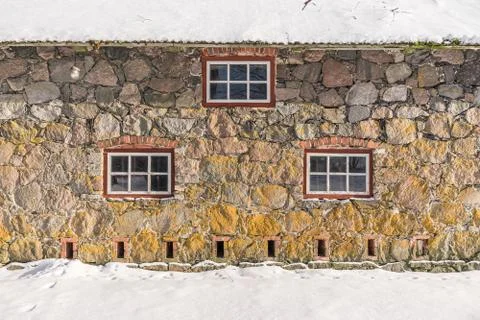 Stone wall texture and windows with red frames, natural background pattern Stock Photos