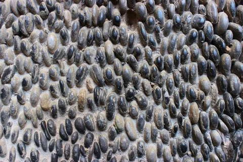 Stone wall texture, road made of small round and oval stones Stock Photos