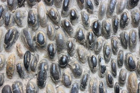 Stone wall texture, road made of small round and oval stones Stock Photos