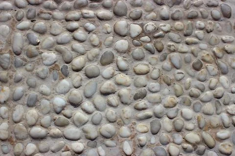 Stone wall texture, road made of small round and sea stones Stock Photos
