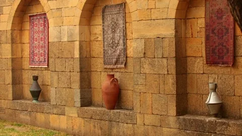 Stone wall with three arched niches. Two decorative rugs hang in the niches. A Stock Footage 318534218