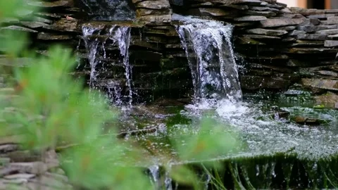 Stone wall with a waterfall in the garden. Artificial decorative waterfall Stock Footage 137120574