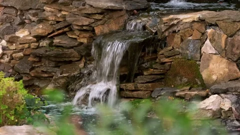 Stone wall with a waterfall in the garden. Artificial decorative waterfall Stock Footage 138408456